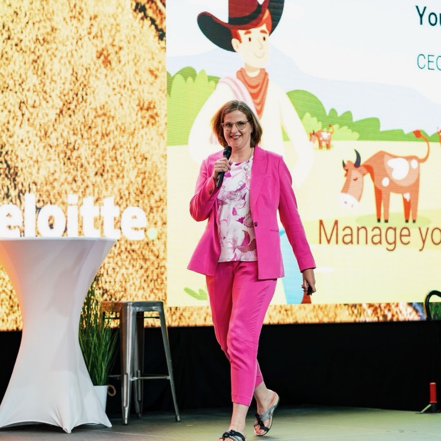 Mocha Shmigelsky walking on stage with a microphone, in a hot pink suit